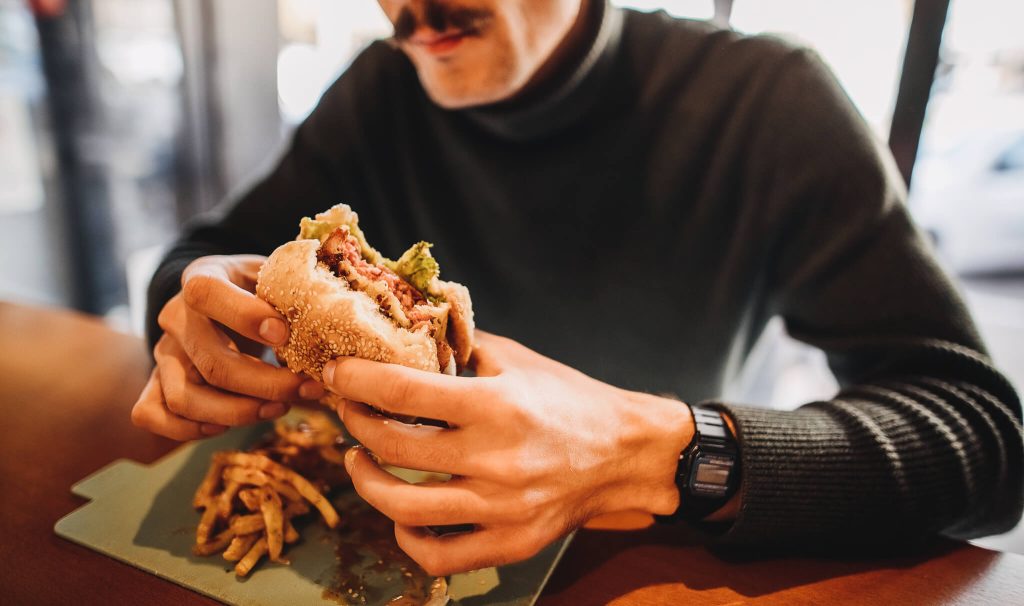 homem comendo hamburguer vegano
