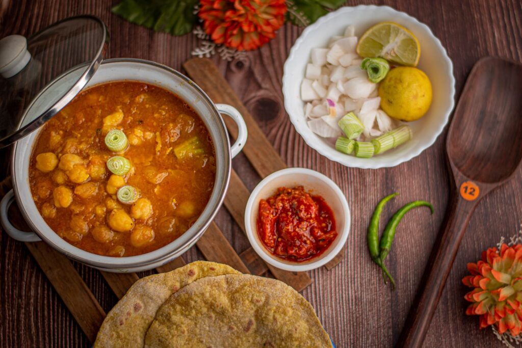 Curry de grão-de-bico em panela, servido com pão e acompanhamentos